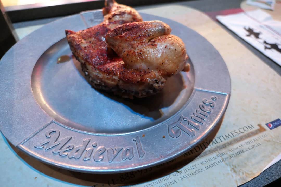 Roast chicken on a silver metal plate that says Medieval Times